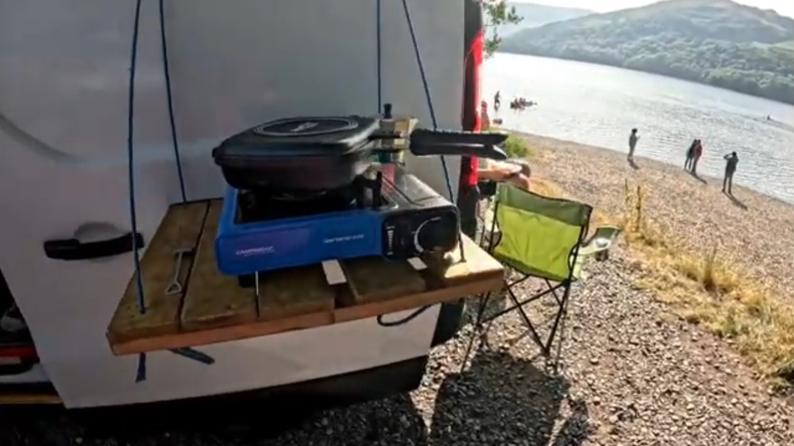 Outdoor cooking setup beside the campervan at a lakeside campsite