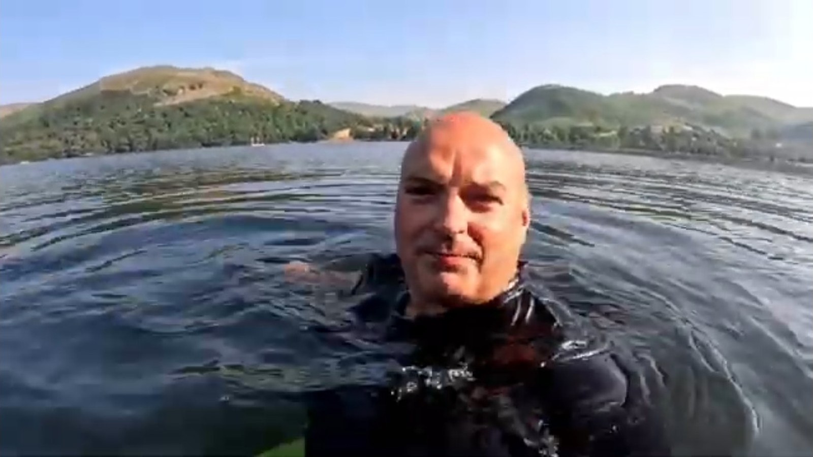 Ian swimming in a mountain lake during a campervan adventure